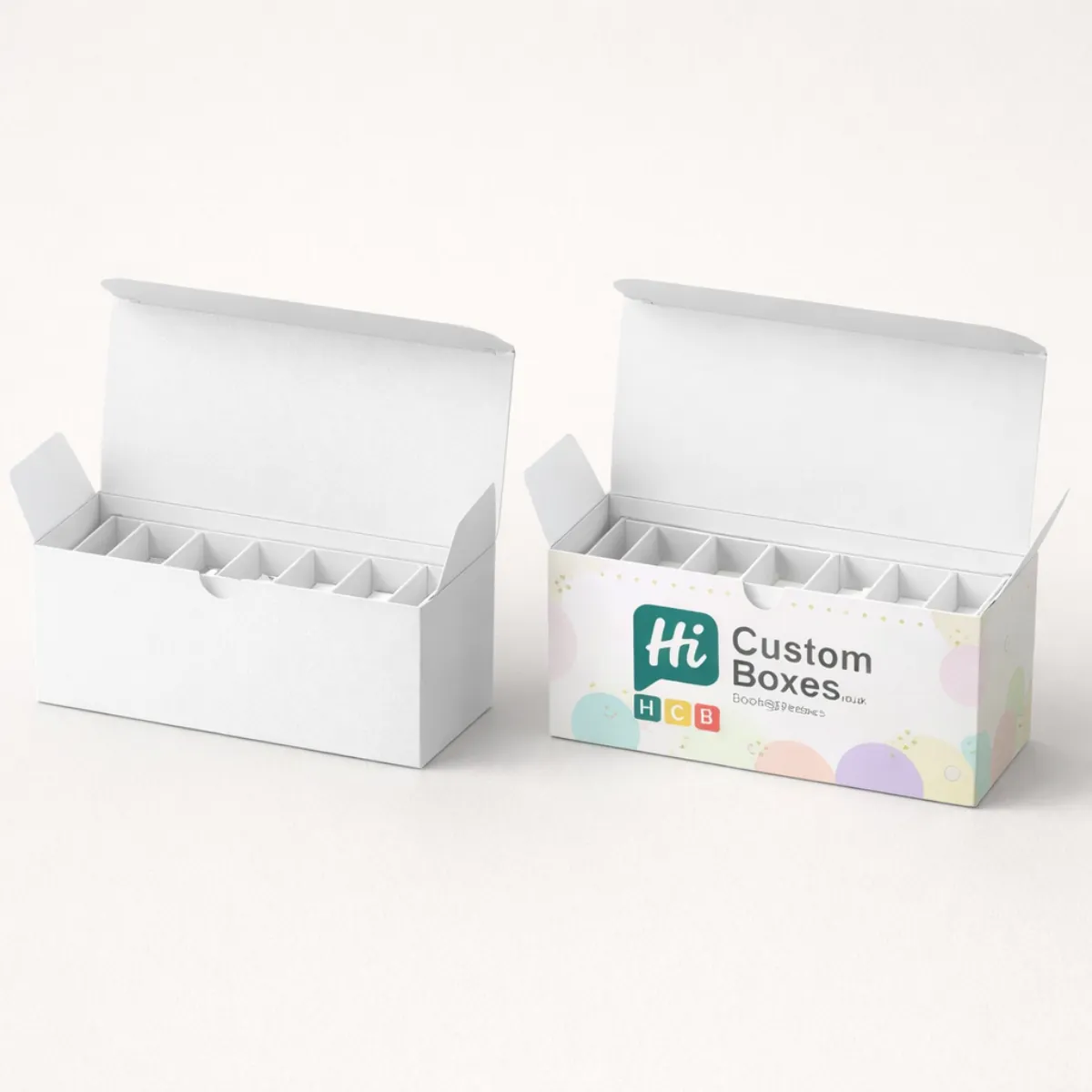 Two elongated white ballotin boxes with dividers- one decorated with a branded pastel circle pattern- class=